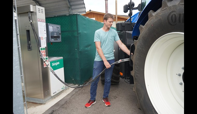 Pascal Pletscher, Mitarbeiter der Müller Energie GmbH, tankt an der hofeigenen Biogastankstelle den CNG-betriebenen Traktor. Er kann nun mit regionalem Treibstoff die Feldarbeit erledigen. (Bild: ©CNG-Mobility / Ökostrom Schweiz)