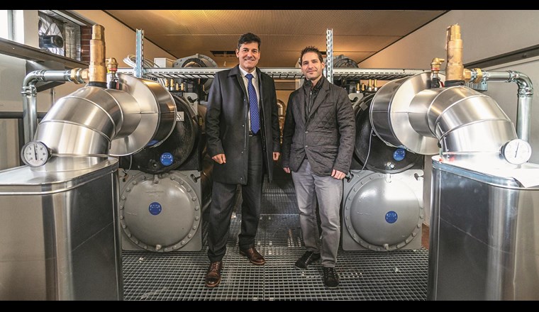 Die Heizzentrale des Wärmeverbundes bestehend aus einem Wärmetauscher, Wärmepumpe und Speicher konnte die AMB im Untergeschoss des bestehenden Pumpwerkes installieren. Direktor Mauro Suà (links) und Lorenzo Bardelli von der Azienda Multiservizi Bellinzona  (AMB) haben nach der erfolgreichen Einführung des ersten Trinkwasser-Wärmeverbundes im Tessin bereits weitere Contracting-Projekte auf dem Wärmemarkt geplant. (Foto: AMB)