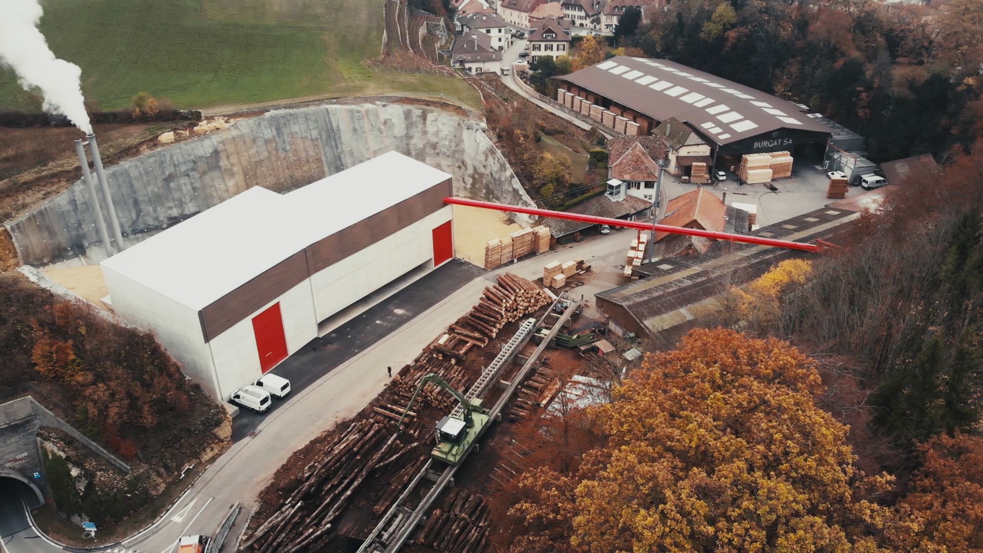 Fig. 1 Das neue Holzheizwerk des Wärmeverbunds BéroCAD in Saint-Aubin-Sauges. Ein Hängeförderband transportiert die Hackschnitzel vom Sägewerk zum Holzheizwerk (links im Bild). (Foto: Viteos)