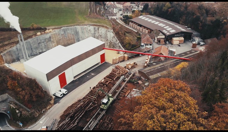 Fig. 1 Das neue Holzheizwerk des Wärmeverbunds BéroCAD in Saint-Aubin-Sauges. Ein Hängeförderband transportiert die Hackschnitzel vom Sägewerk zum Holzheizwerk (links im Bild). (Foto: Viteos)